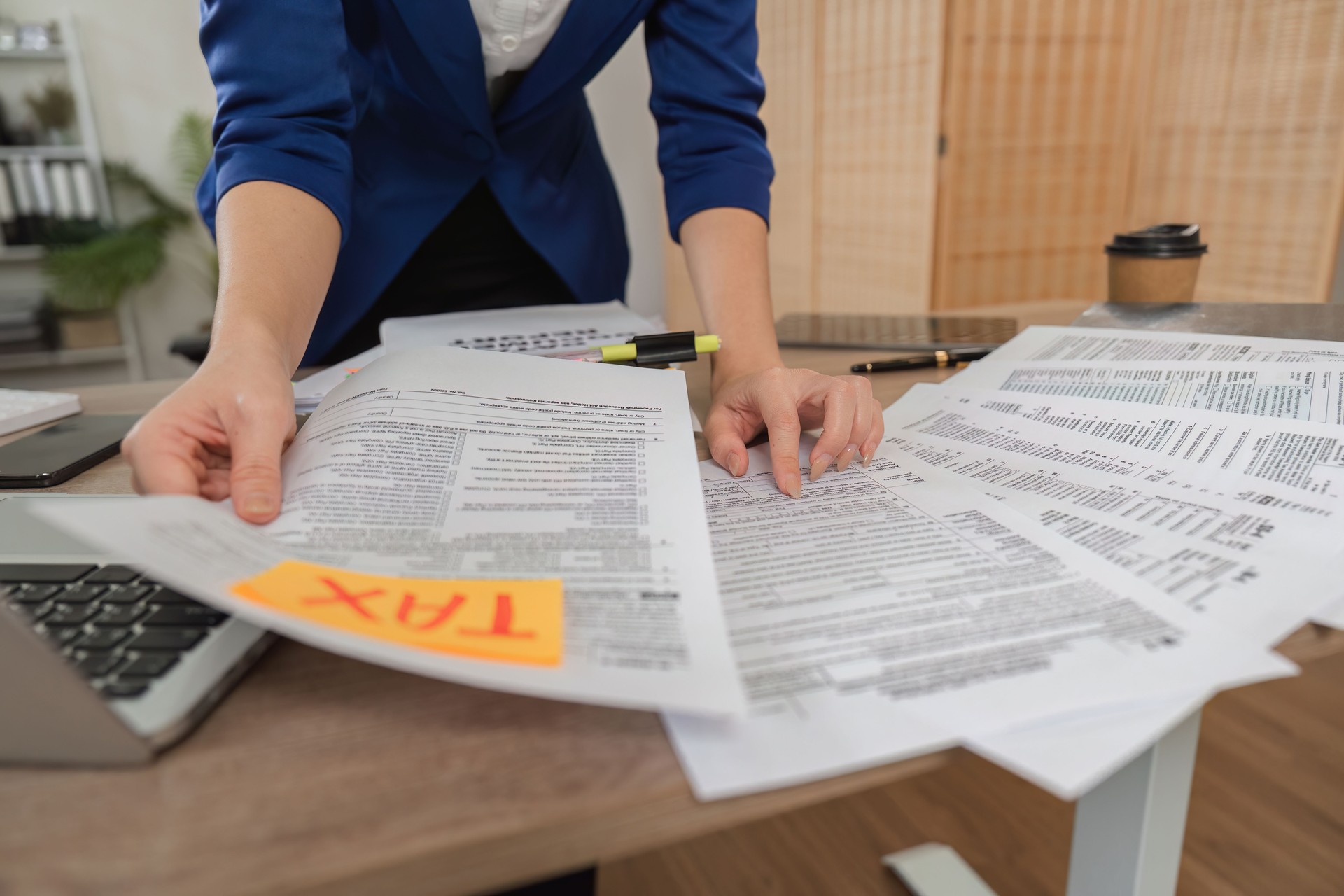 Tax preparation and analysis. Woman sorting tax documents in a modern office environment.
